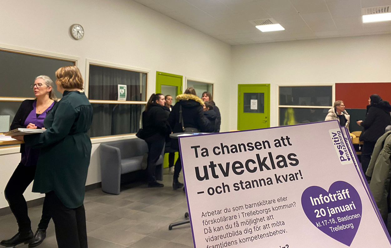 flyer i förgrunden, personer som pratar i smågrupper i bakgrunden