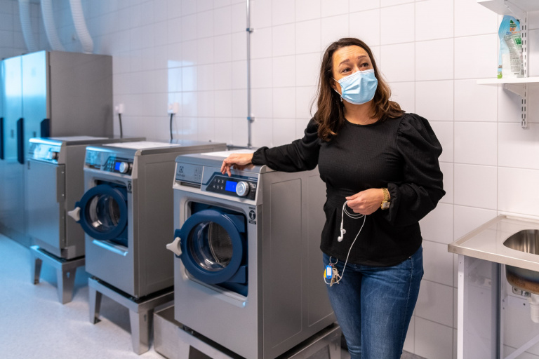 Kvinna visar upp tvättmaskiner i tvättstuga.