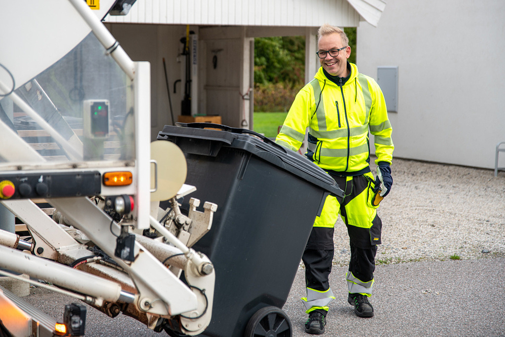 Visar tömning av avfallskärl i sopbil.