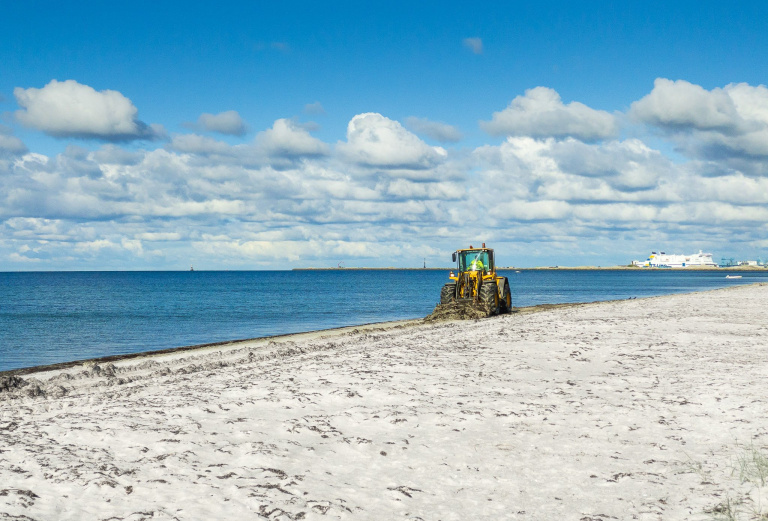 Maskin rensar tång på stranden.