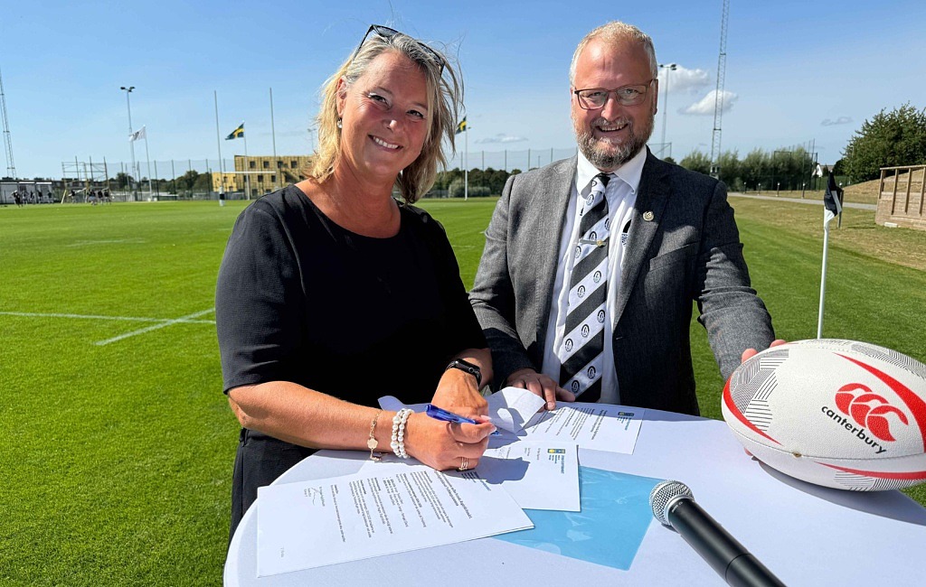 Kvinna och man vid bord med papper och rugbyboll