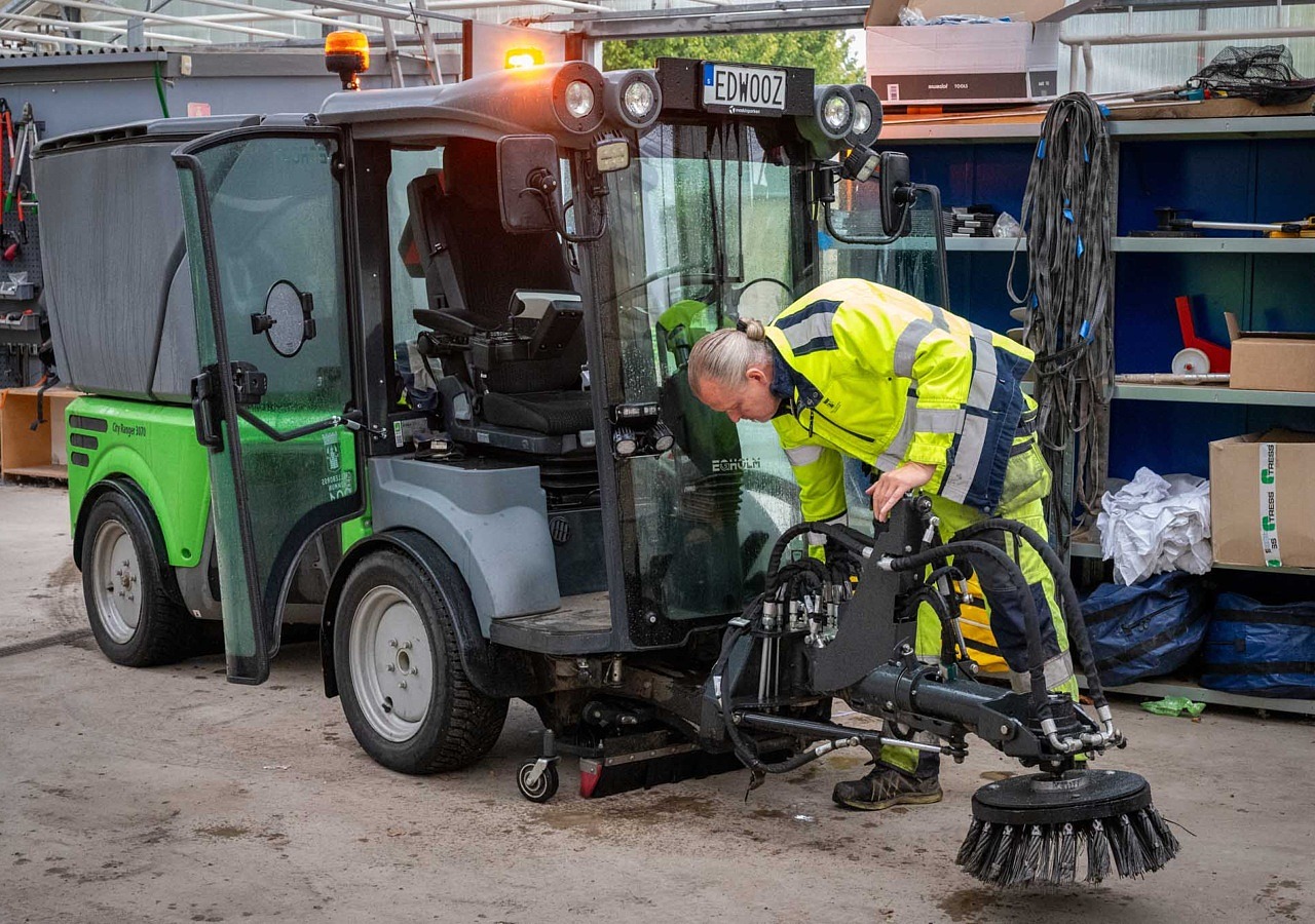 Man i arbetskläder vid liten traktor.