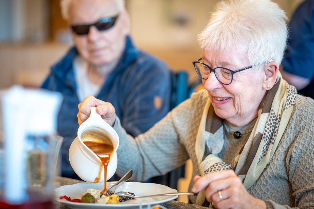 Kvinna häller upp sås på sin tallrik.